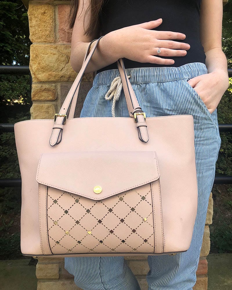 Maggie sports a dusty rose Michael Kors tote bag with a front pocket, black piping, and gold buckles.