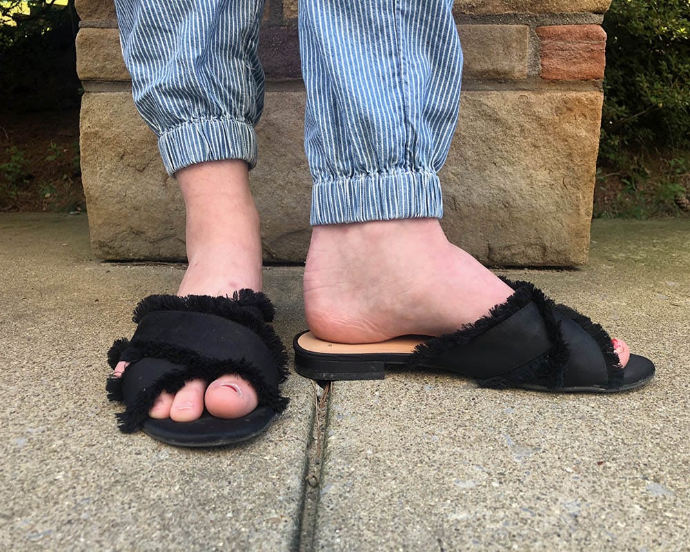 These sandals are flat black criss-cross slides with frayed edges.