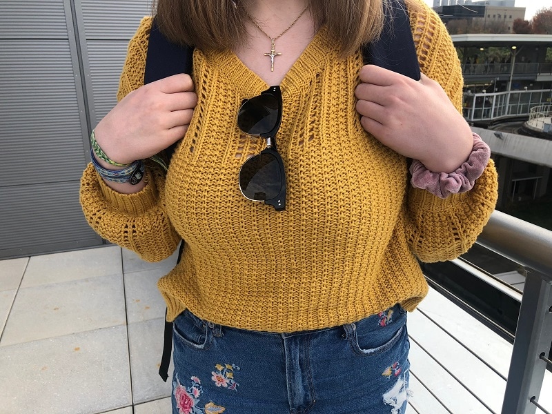 Maria wears a chunky knit mustard sweater with baggy sleeves.
