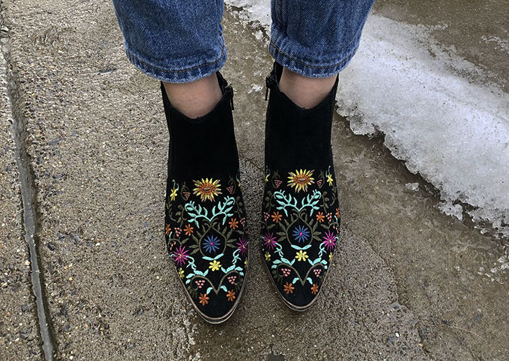 Morgan wears black booties with blue, yellow, purple, and brown floral embroidery.