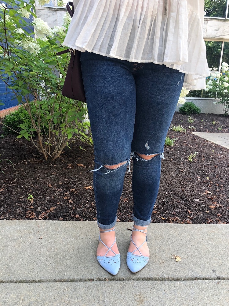 Sarah sports dark-washed distressed denim jeans with baby blue pointed flats.