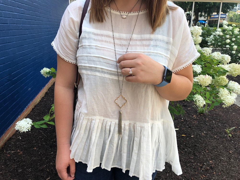 Sarah wears layered gold necklaces with tassles and gems.