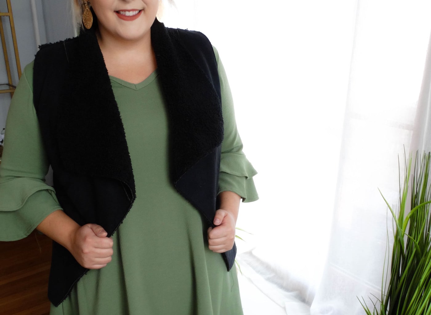 West Virginia University student Sydney wears a green dress with layered ruffled sleeves and a black furry vest.