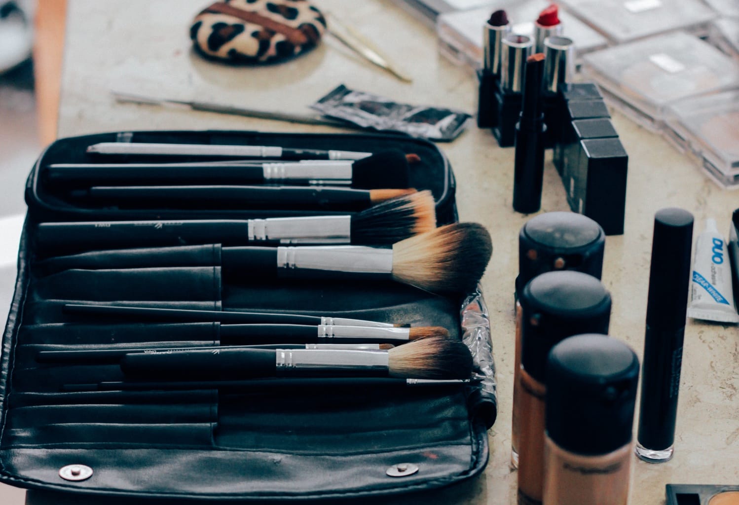 Makeup brushes and foundations laid out on a table