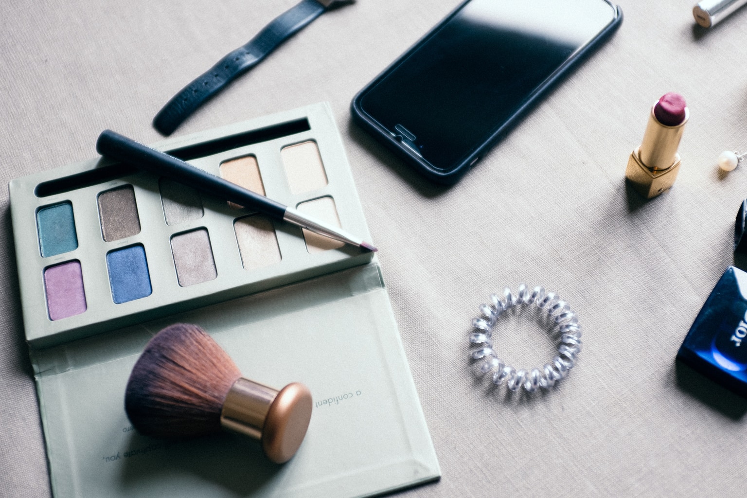 Makeup on a table with iphone and eyeshadow