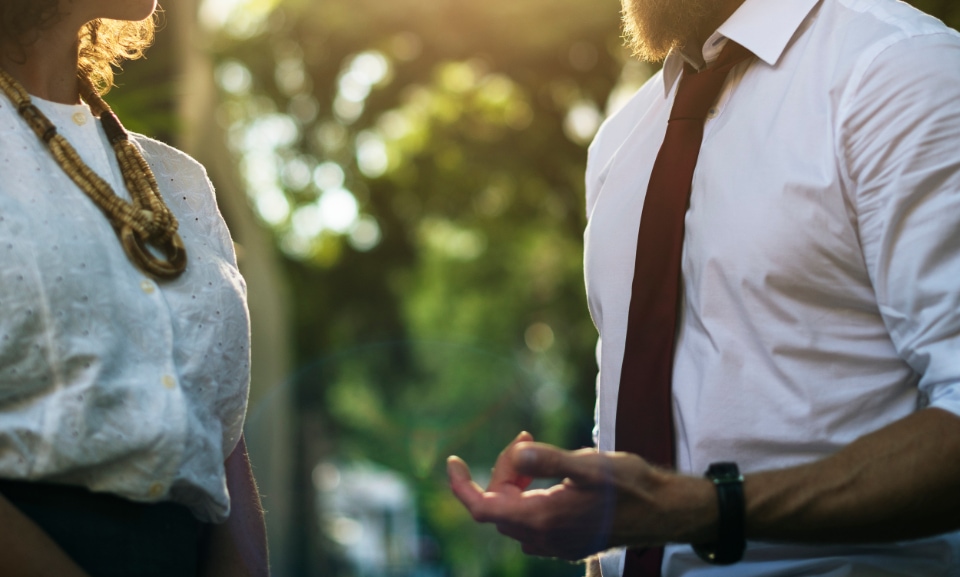 Woman talking to a man in a tie in public