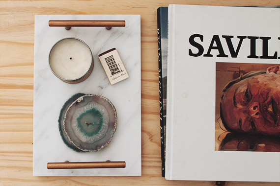 Photo with a marble tray an two books. The tray has a candle, small box, and geode coasters on it.