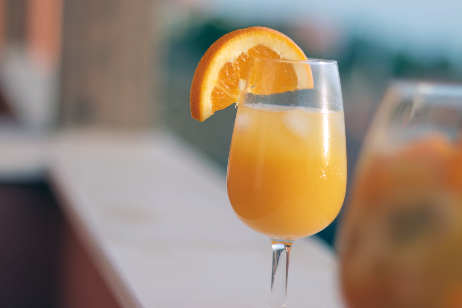 A mimosa in a glass with an orange wedge