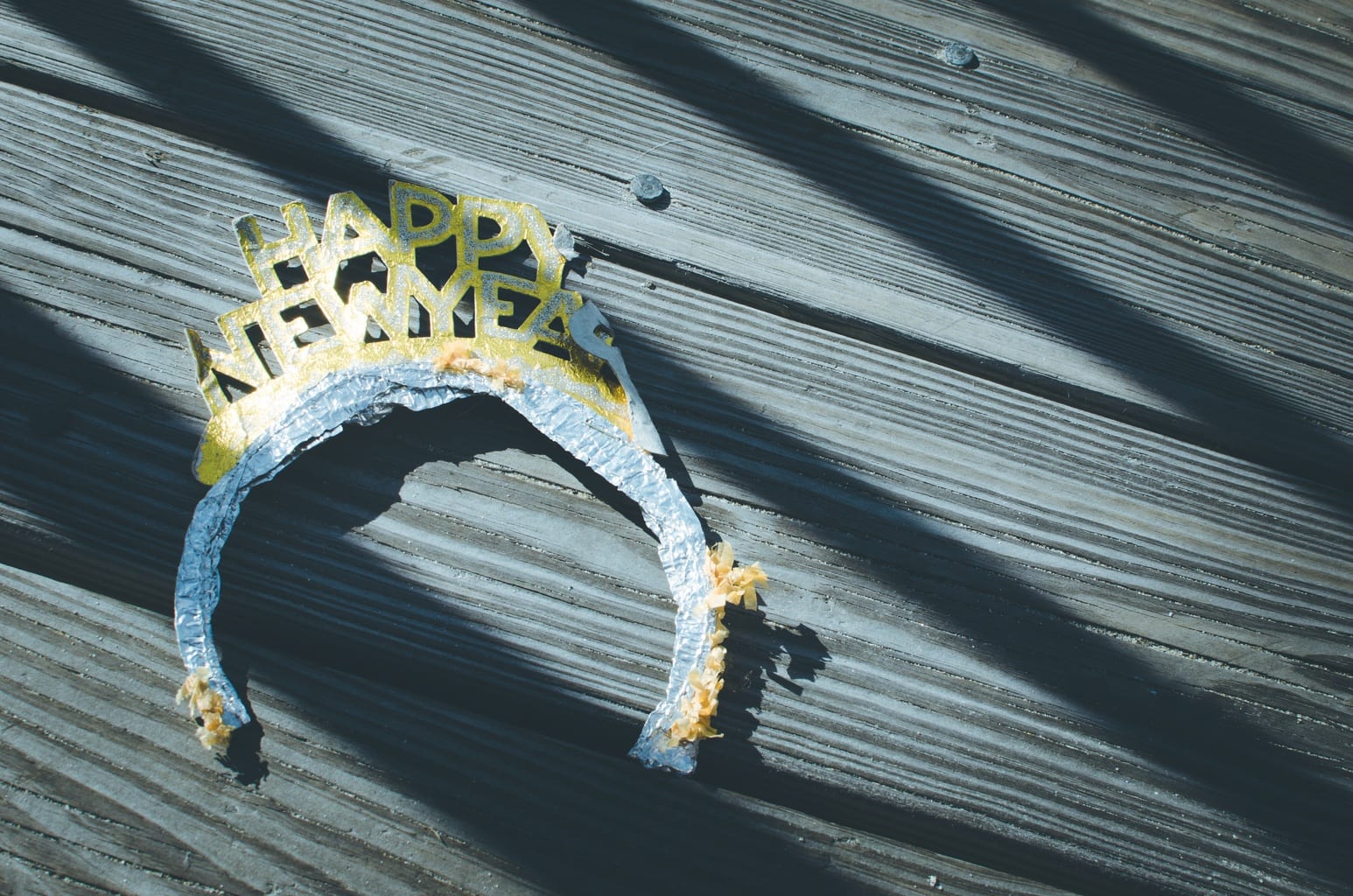 A New Years headband lays on a wooden porch.