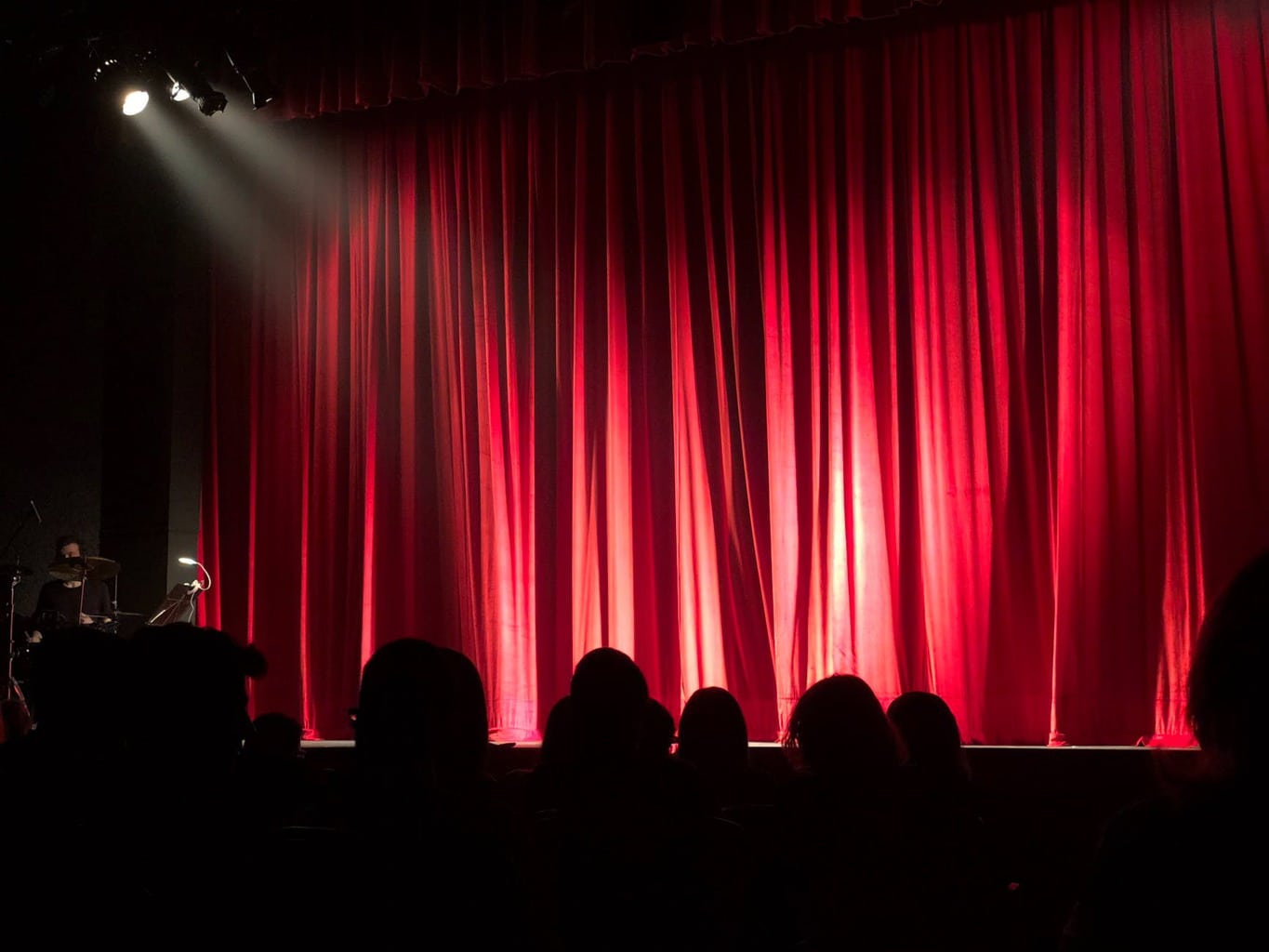 People at a theater with a red curtain and lights