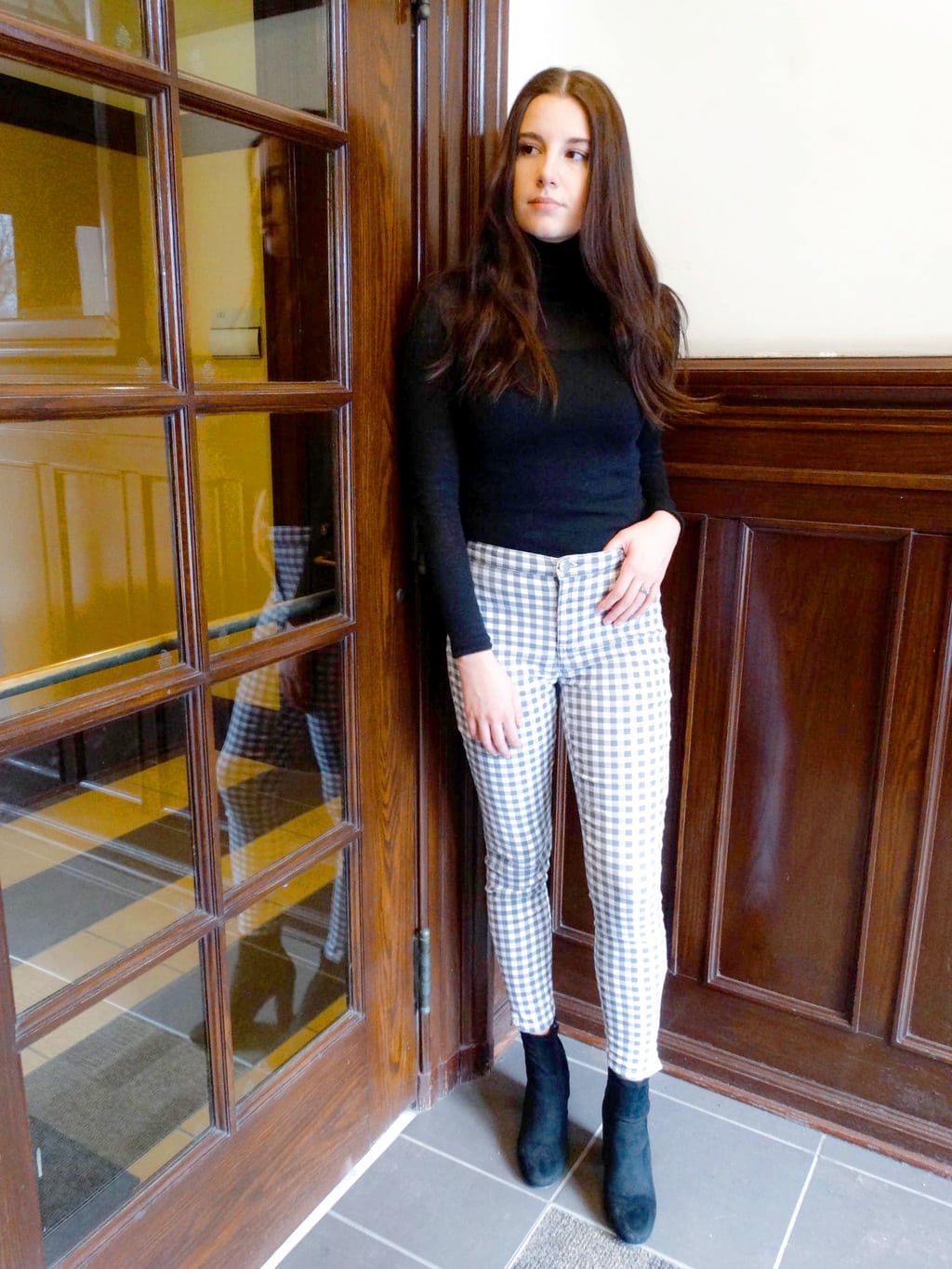 A West Virginia University student wears statement grey and white checkered pants with a long-sleeve black turtleneck and chunky black booties.