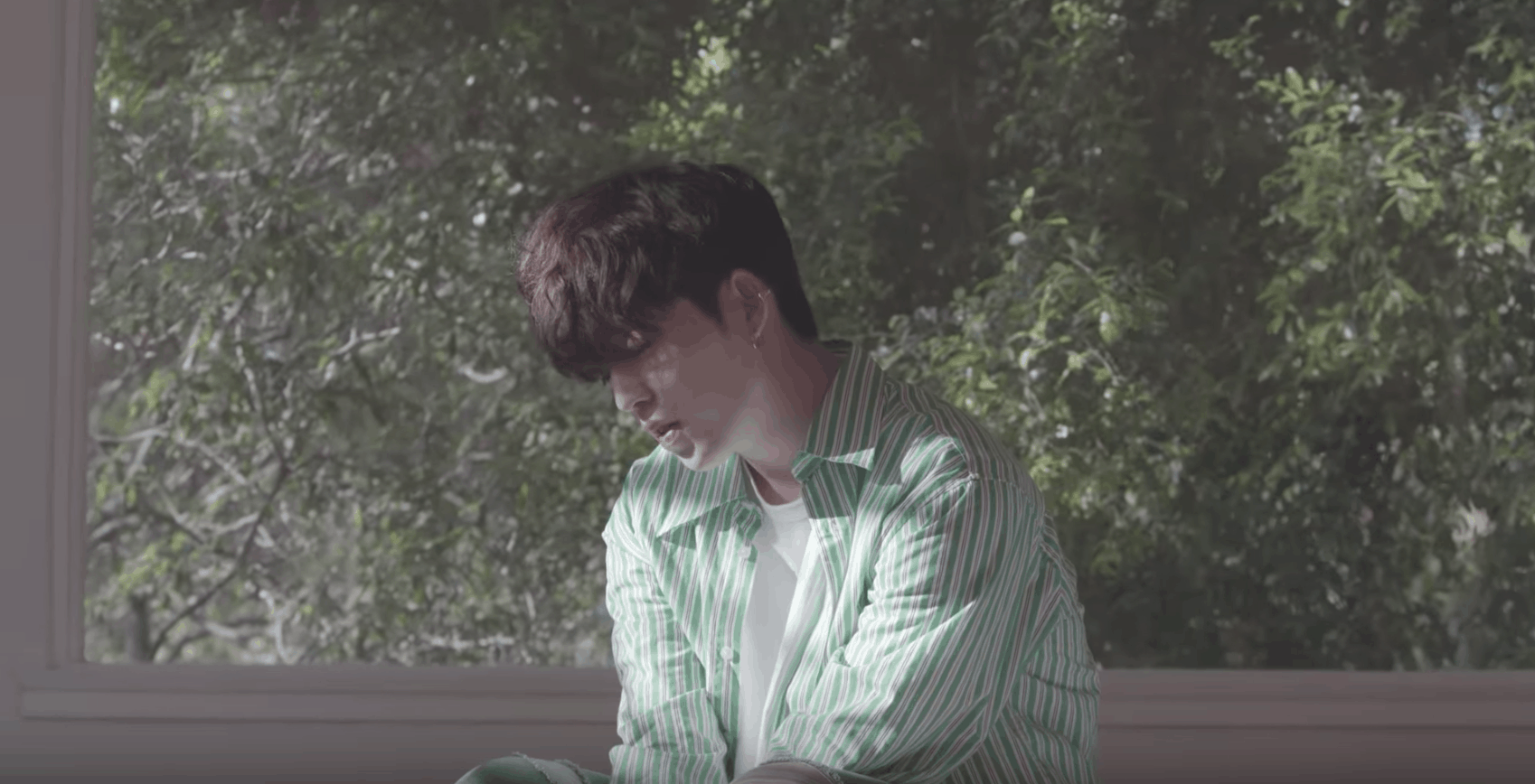 Seventeen kpop fashion: Don't Wanna Cry music video. Member wears green striped shirt in front of a window.