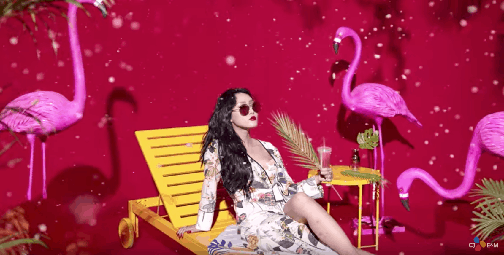 Mamamoo "Yes I Am" fashion: Hwasa wears a floral dress and sunglasses with a red lip while lounging in front of flamingos in the music video