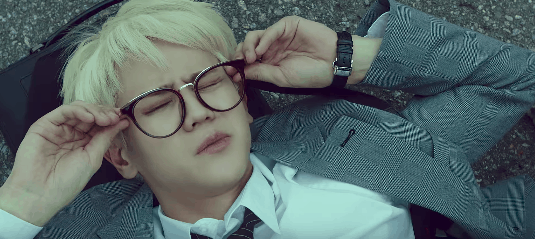 Highlight can be better music video - screenshot of band member with blond hair wearing glasses and lying on the ground