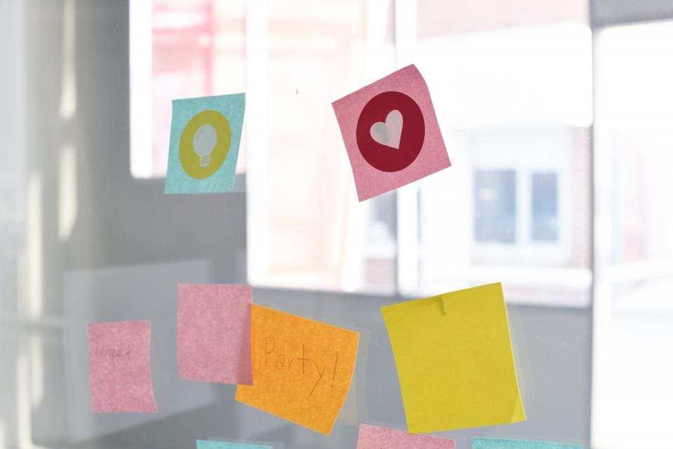 Pink, blue, orange, and yellow sticky notes on a window