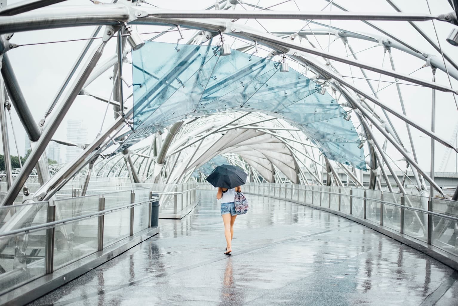 What to wear on a rainy day in summer: Girl wears shorts, black umbrella, printed backpack, white tank