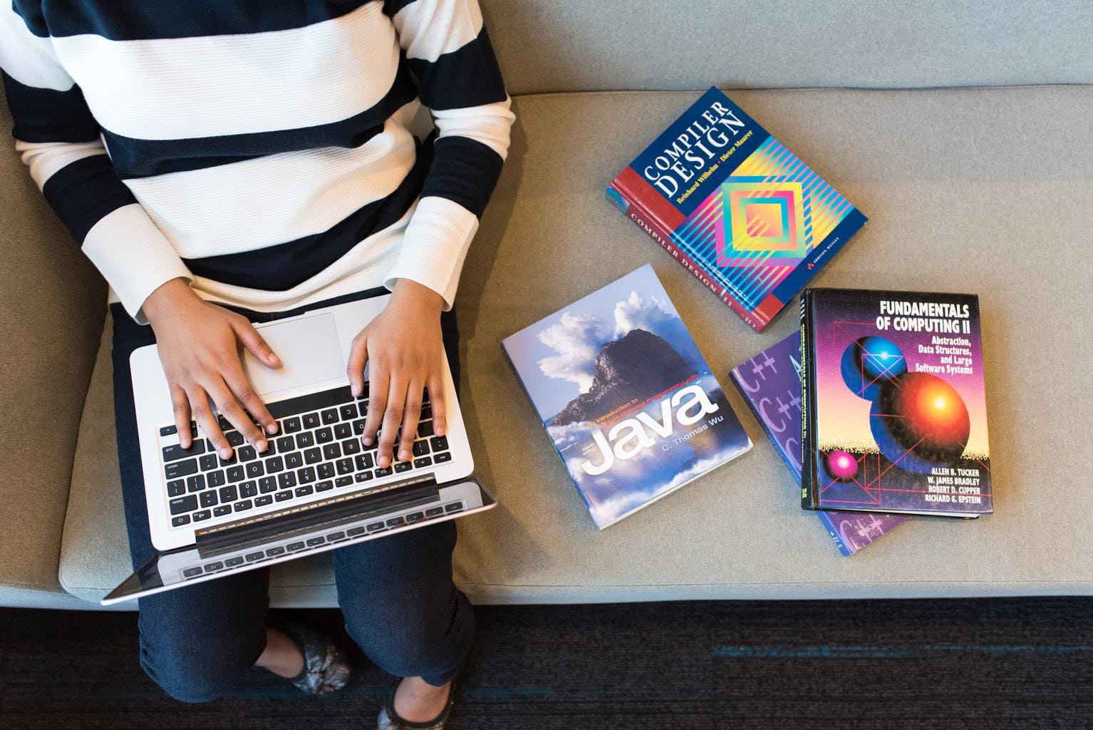 Person on laptop with textbooks.