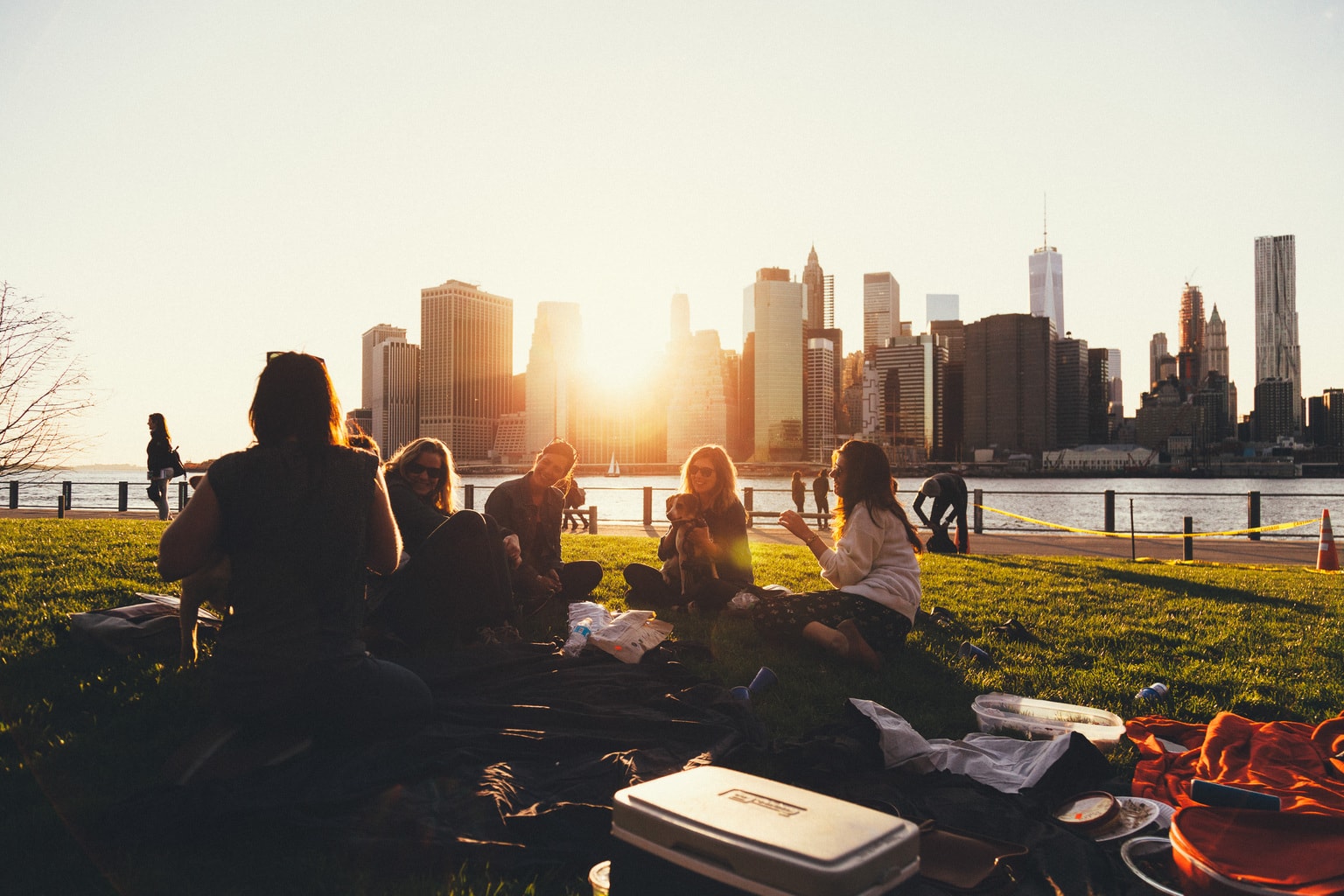 Group of friends on grass with city in the background.