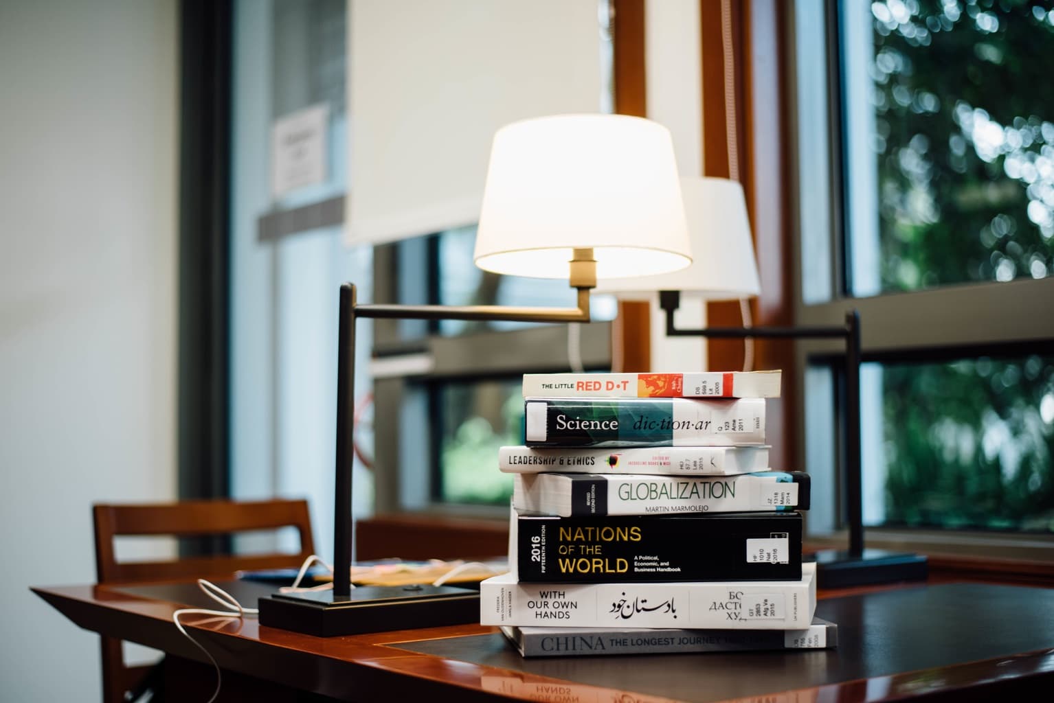 table with stacks of books in a naturally lit studying area