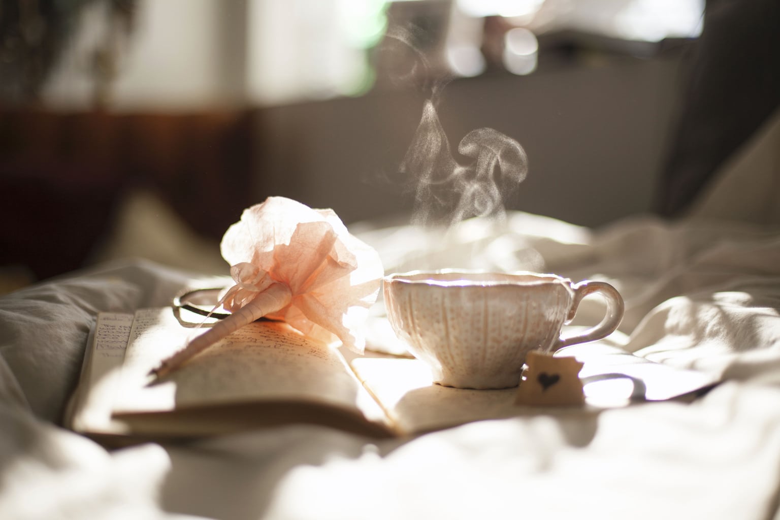 dainty pink teacup on top of journal with a pen