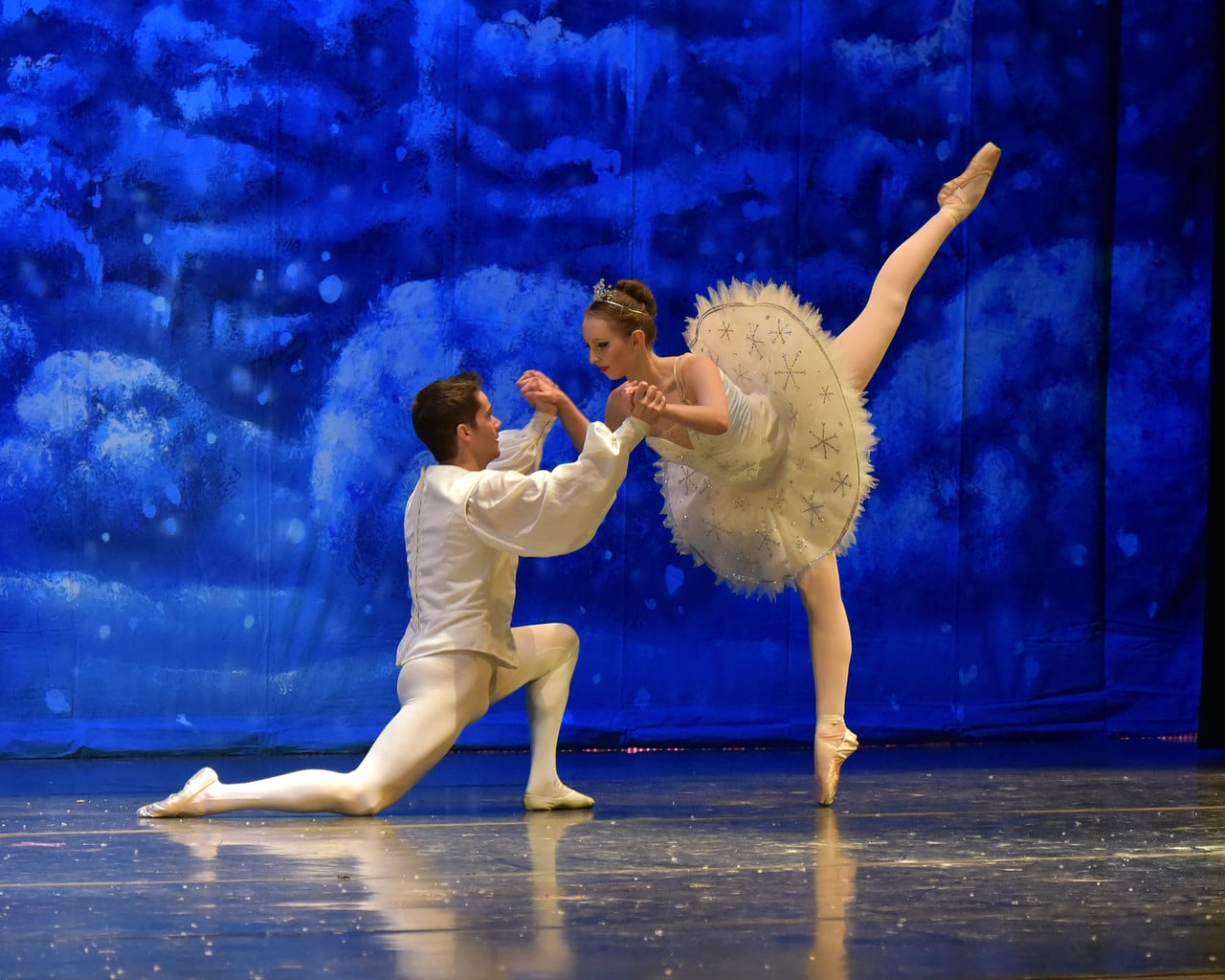 Two dancers, one man and one woman, in front of a blue backdrop in The Nutcracker Ballet