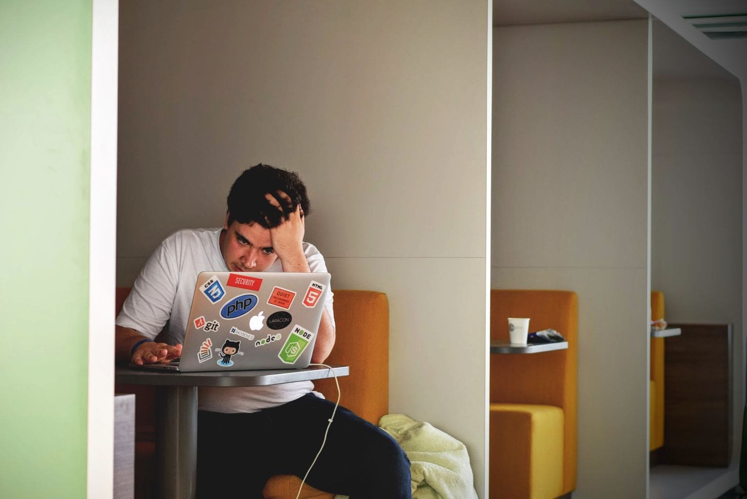 A stressed student working on a laptop in a coffee shop