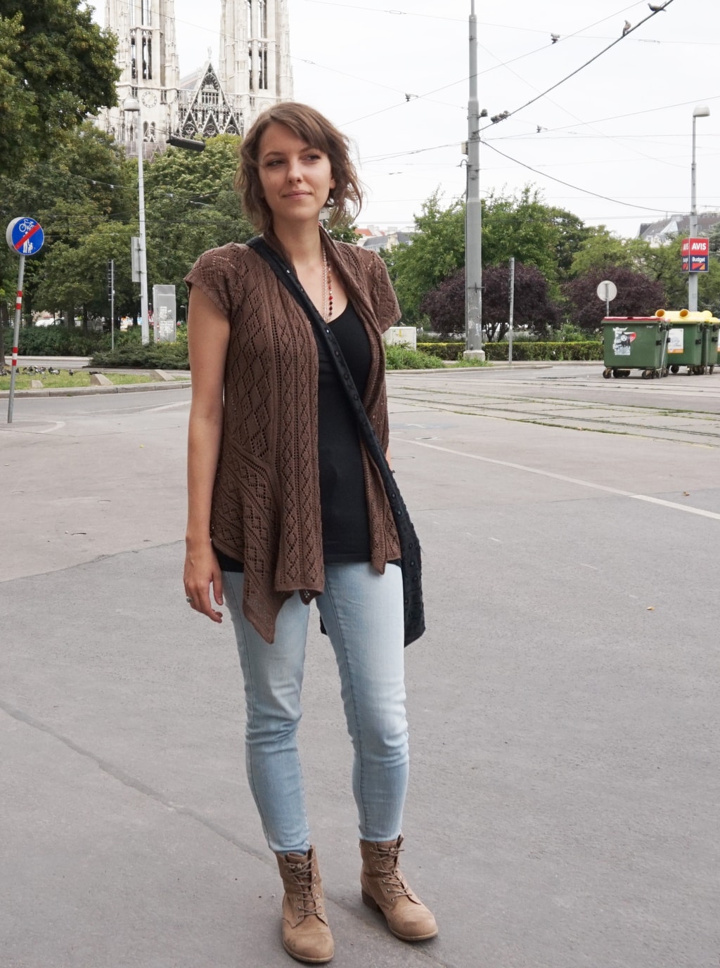University of Vienna street style: Student wearing a black top, light wash jeans, and a brown cardigan and boots