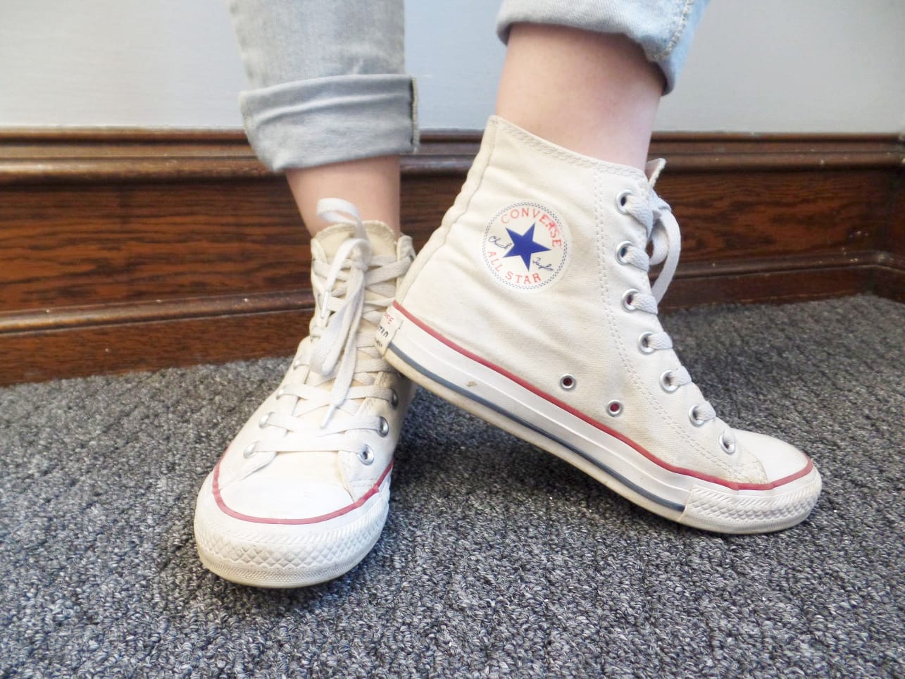 Veronica sports high-top white Converse sneakers with her light-wash jeans cuffed.