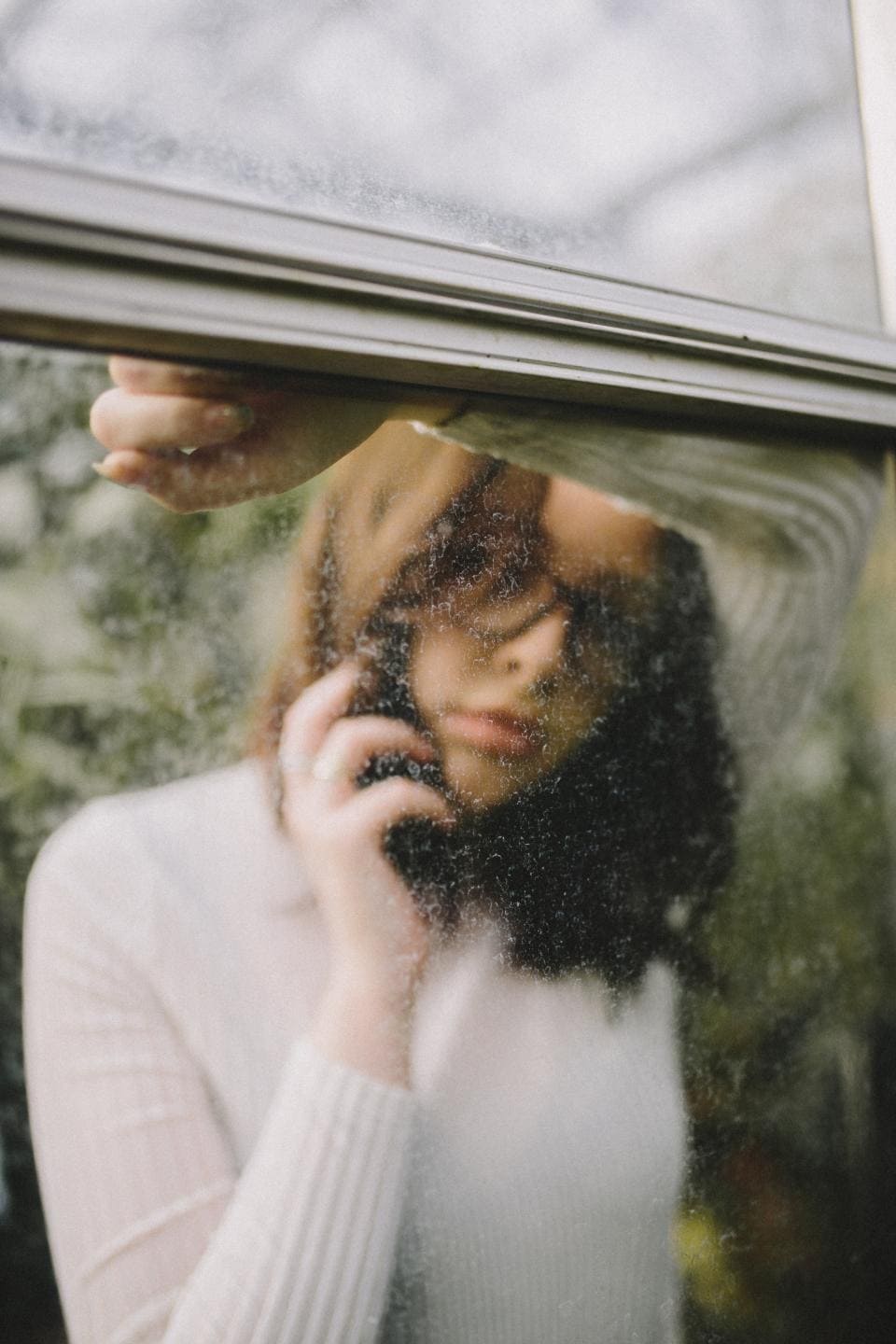 Woman behind dirty car window on phone