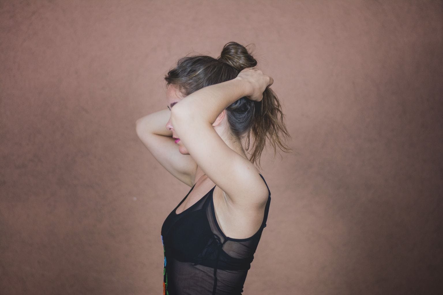 Woman getting ready to exercise, wearing a sports bra and tank in black