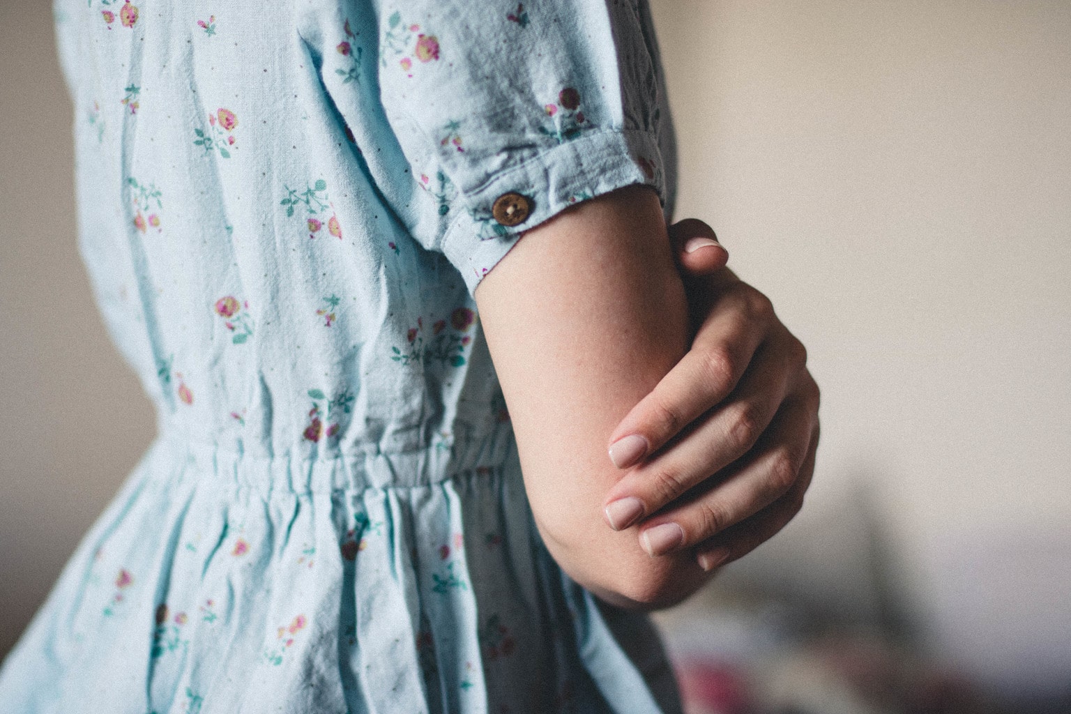 Close-up of the torso of a woman wearing a blue floral dress.