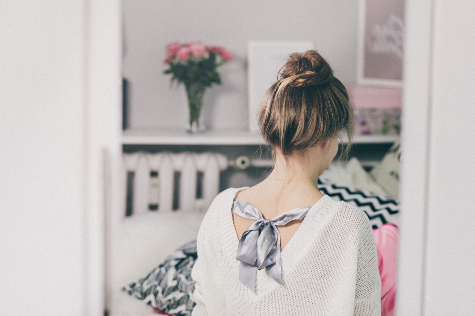 Woman in her room wearing a bow back sweater