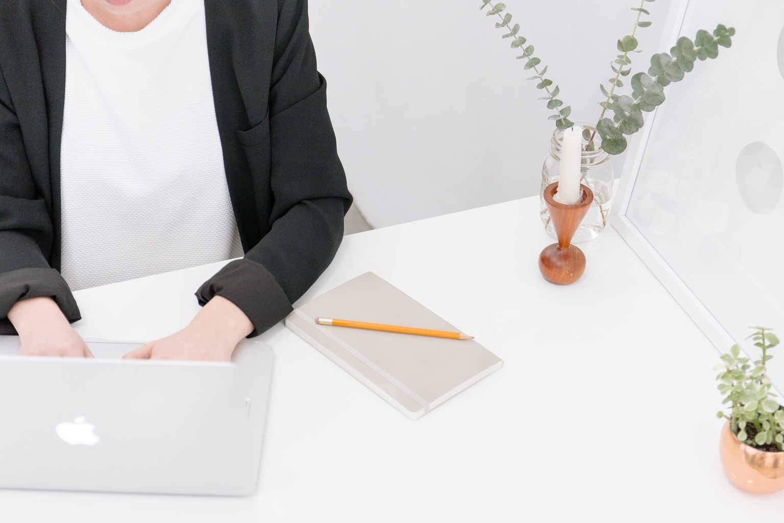 Woman sitting at a desk typing on a Macbook laptop