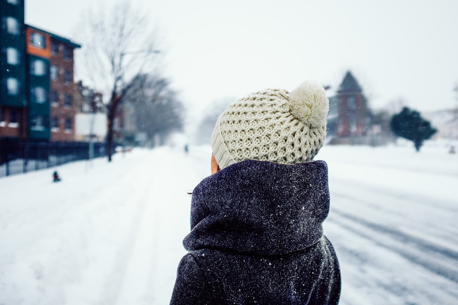Woman wearing a beige winter knit hat in the snow