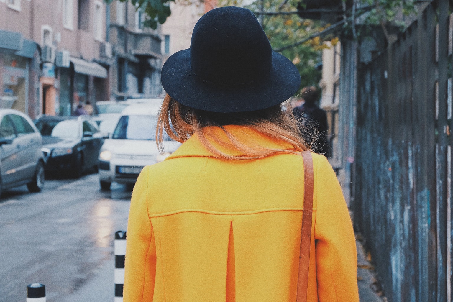 Woman wearing a yellow coat and black rounded hat