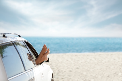 Woman at the beach with her feet out of the car window