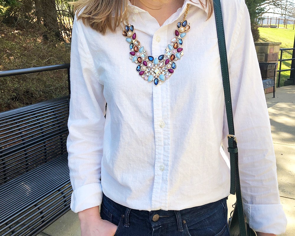 Molly's white linen button down is a great basic staple. She pairs it with a dramatic gold necklace full of navy, baby blue, and maroon jewels.