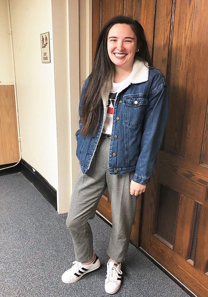 West Virginia University student Rachel wears a casual daytime look that consists of a basic white Levi's tee tucked into grey loose checkered slacks, an oversized denim jacket lined with shearling, and white Adidas allstar sneakers.