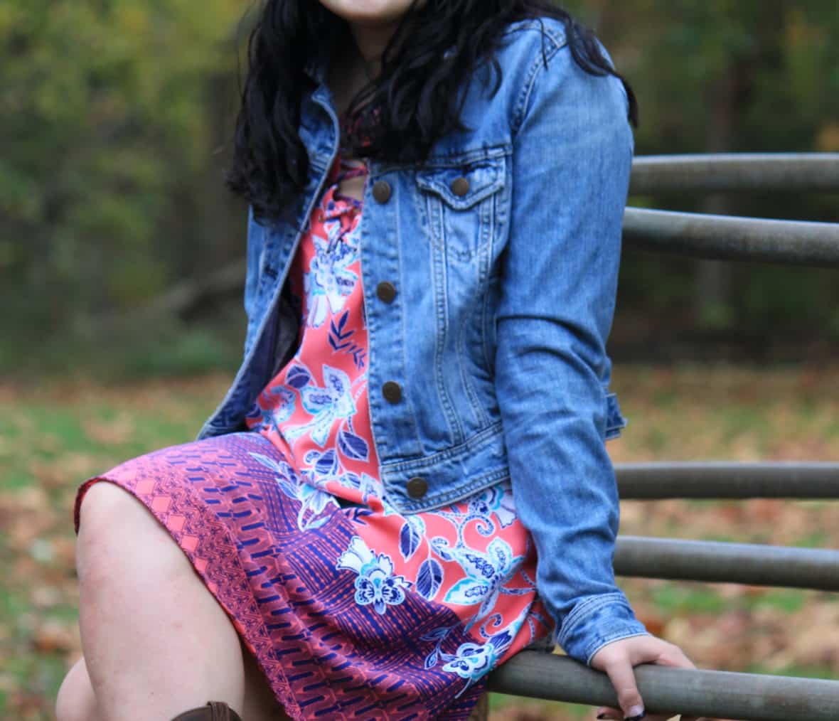 Abbey wears a coral, pink, and purple floral print summer dress with a distressed denim jacket.