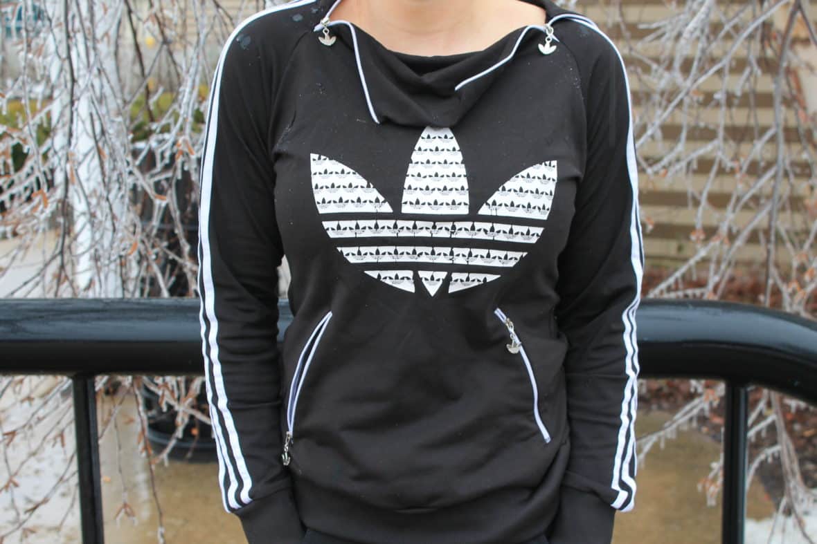 This GVSU student wears a black Adidas tracksuit hoodie with a cowl zipper collar and white detailing.