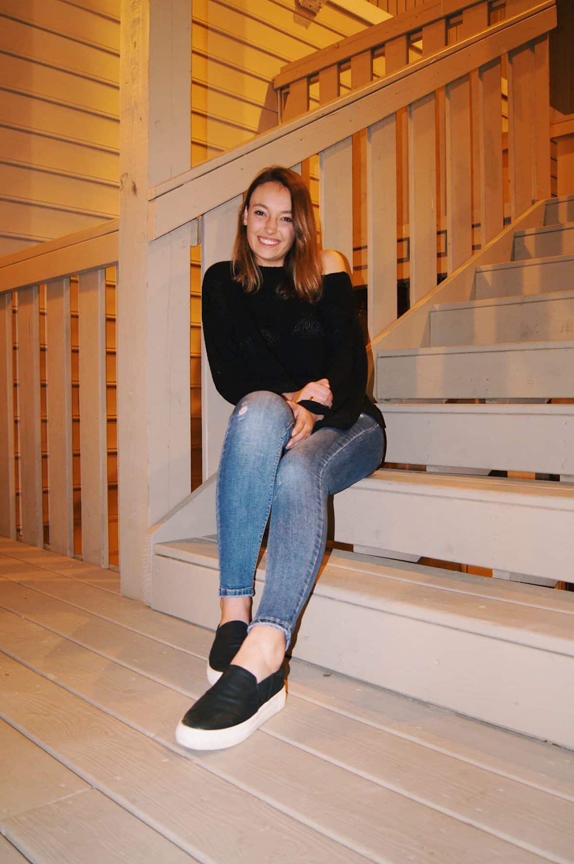 Virginia Tech student wears a black cut-out shoulder sweater, light-wash jeans, and black slip on shoes.