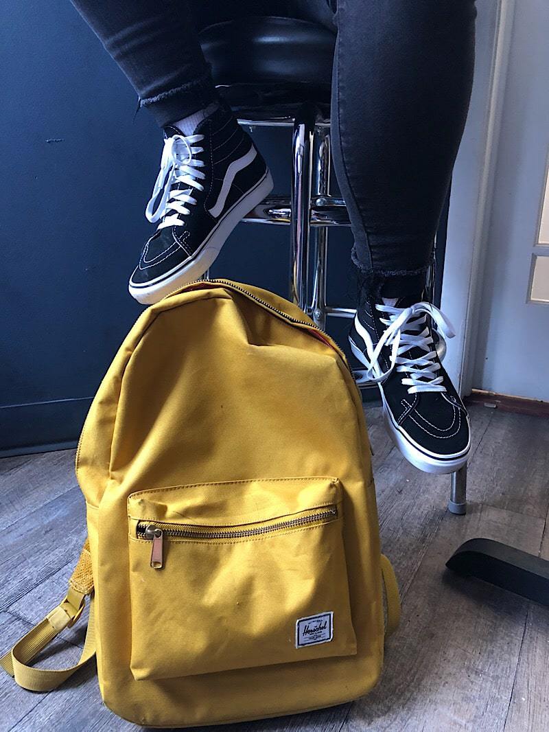 Tiana sports Vans Sk8-Hi sneakers and a yellow Hershel Supply Co. backpack.