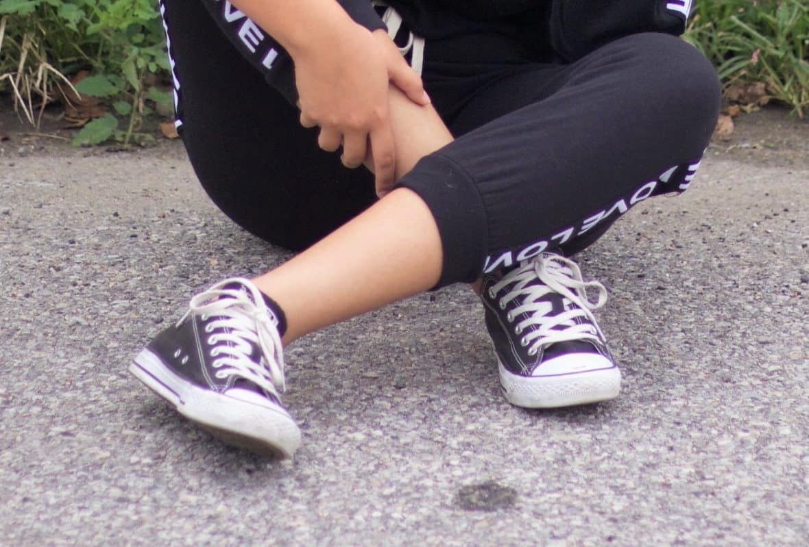 Nathaly wears black low-top Converse sneakers with white laces.