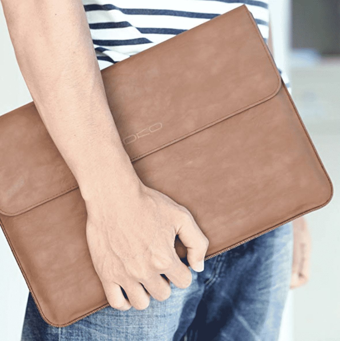 hand holding a leather laptop sleeve