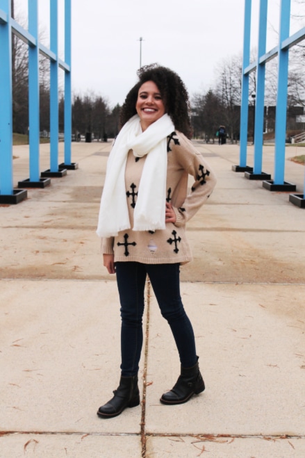 Grand Valley State University fashion: Woman wearing a cross sweater and black jeans