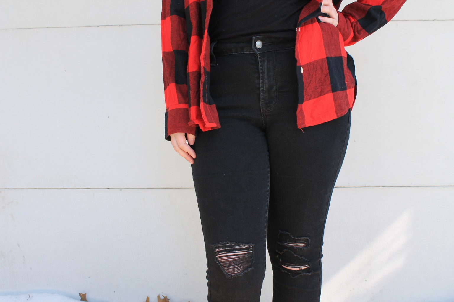 These high-waisted black denim jeans are distressed slightly around the knees.