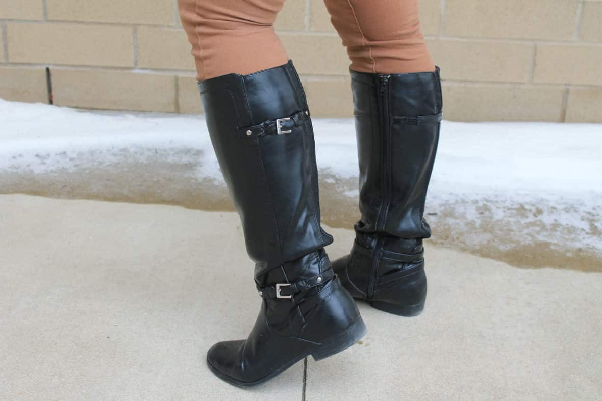 Leslie wears black riding boots with two buckles over her jeans.