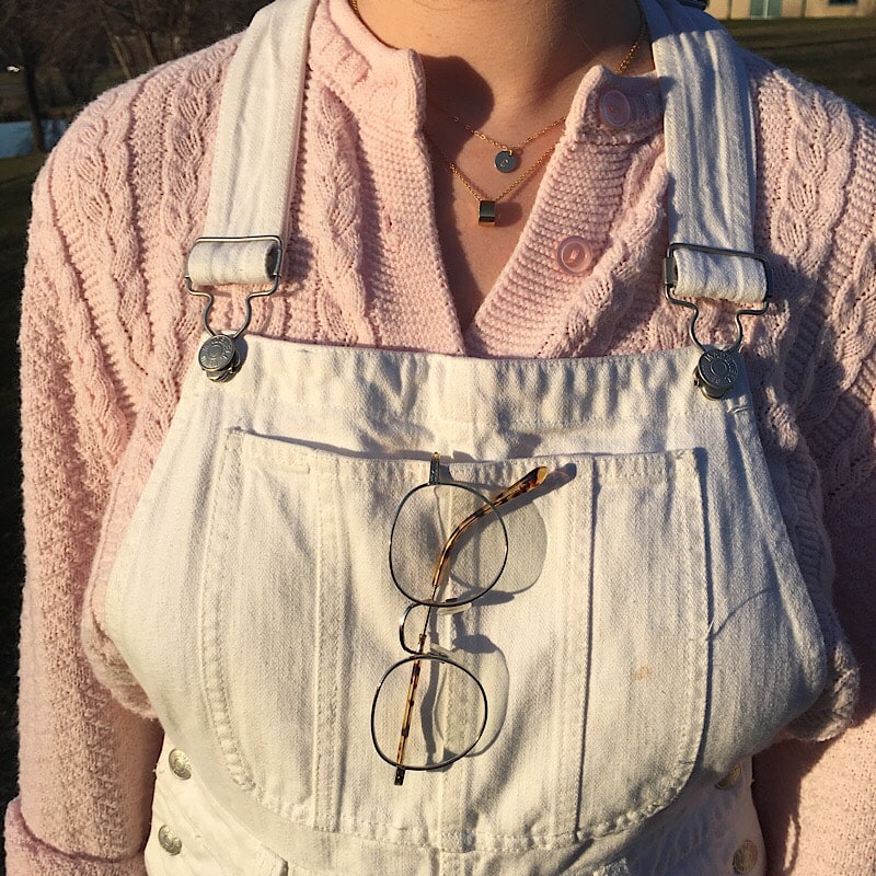 Abby wears thin brushed silver wire-rimmed glasses with her overalls.