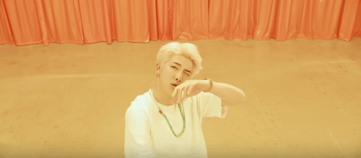 RM in all white with a green necklace