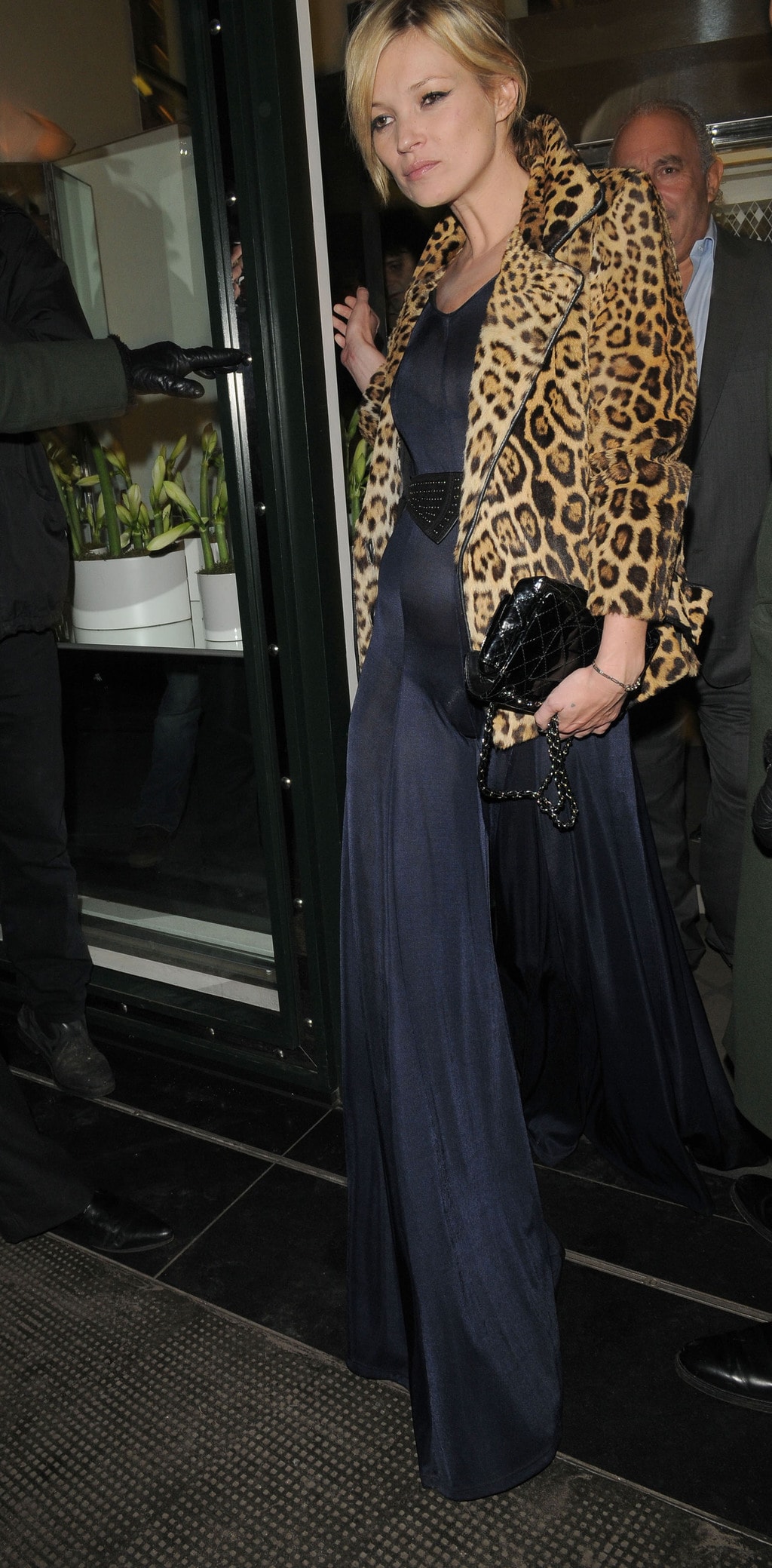 kate moss in a navy jumpsuit and leopard blazer carrying a clutch